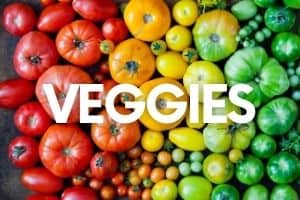 Heirloom tomatoes arrayed in rainbow order. A text overlay says "Veggies."