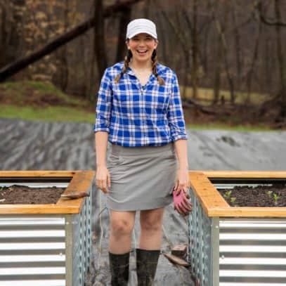 Woman standing between two raised beds, smiling