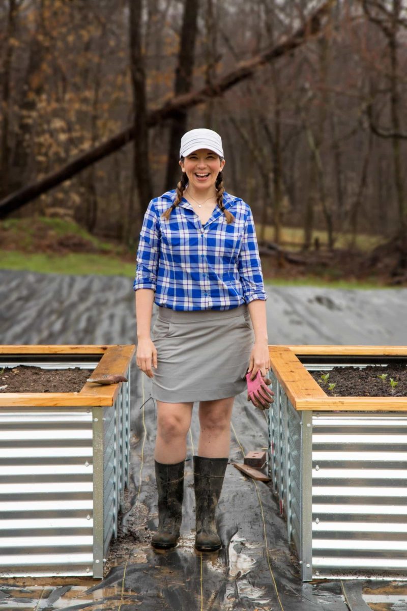 Woman standing between two raised beds, smiling