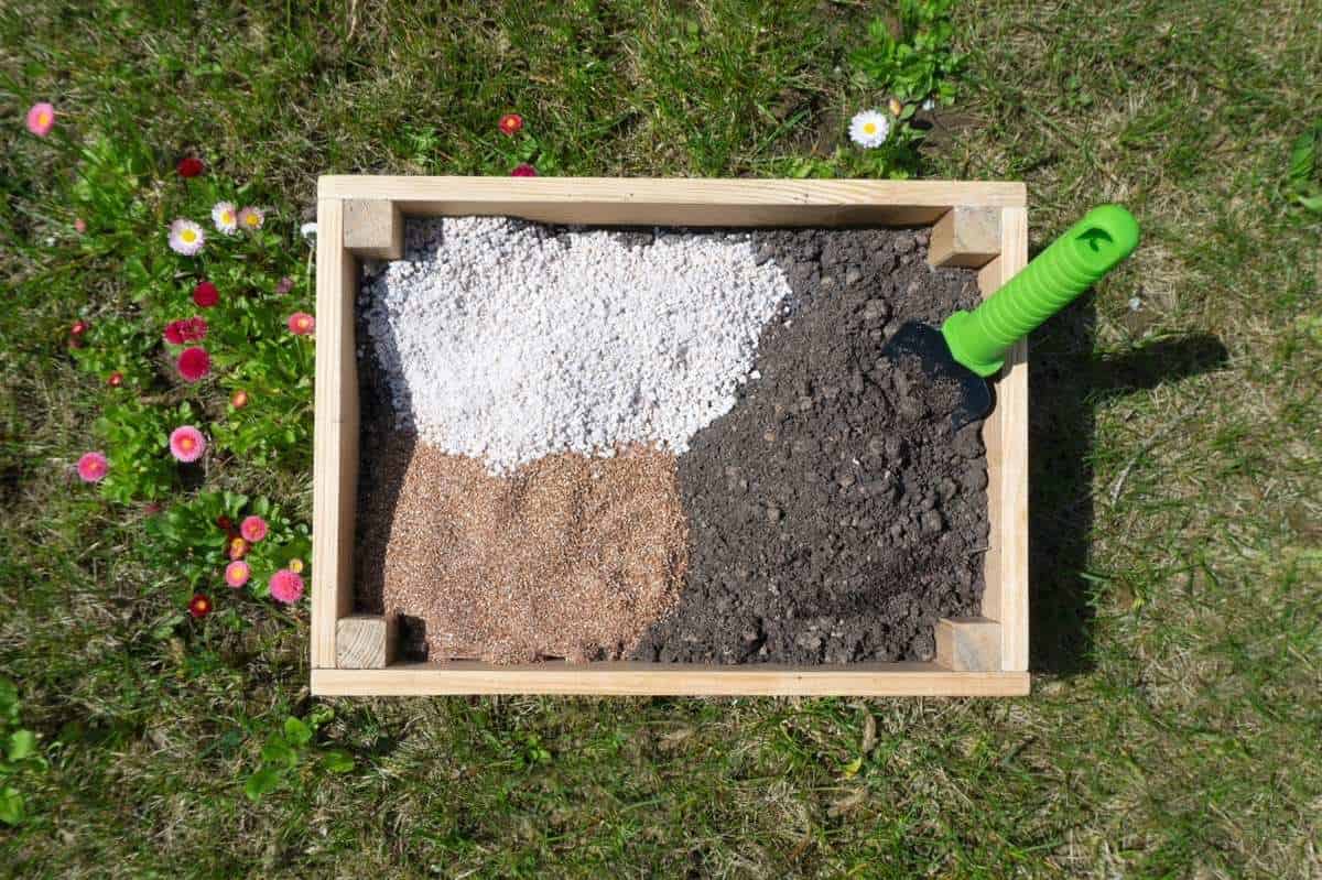 Soil mix components in a wooden bin, with a trowel resting on the side.